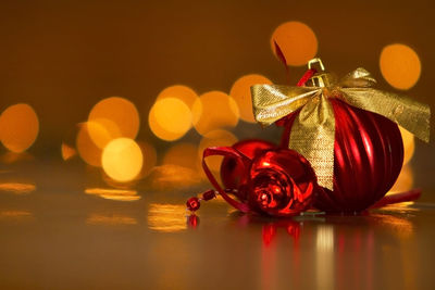 Close-up of christmas bauble against illuminated lights on table