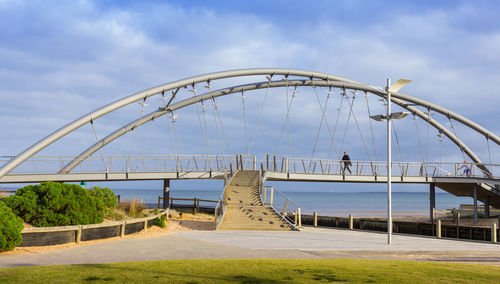 Bridge over river against cloudy sky