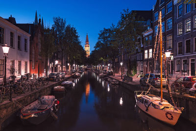 Boats moored in canal amidst buildings at night