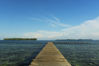 Pier over sea against blue sky