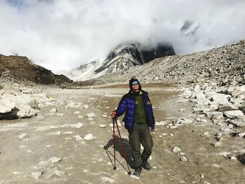 Full length of man standing on mountain during winter against sky