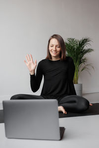 Portrait of young woman using digital tablet while sitting on sofa at home