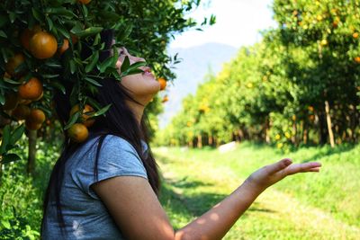 Side view of young woman against tree