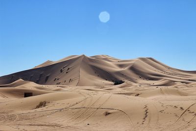 Scenic view of desert against clear blue sky