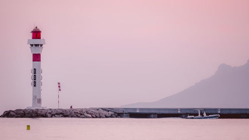 Lighthouse by sea against clear sky