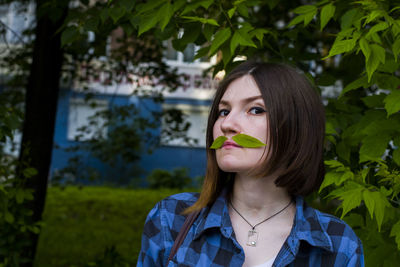 Portrait of young woman against tree