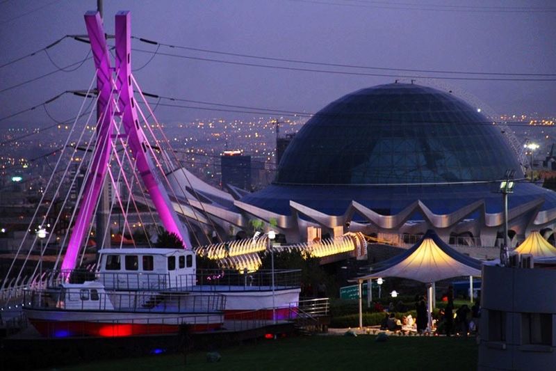 architecture, built structure, building exterior, city, illuminated, sky, night, ferris wheel, modern, travel destinations, famous place, capital cities, connection, arts culture and entertainment, outdoors, travel, bridge - man made structure, low angle view, tourism, multi colored