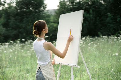 Full length rear view of man holding woman standing on field