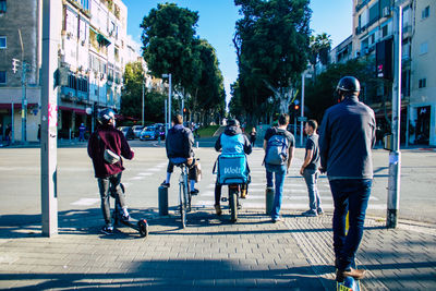 Rear view of people walking on city street