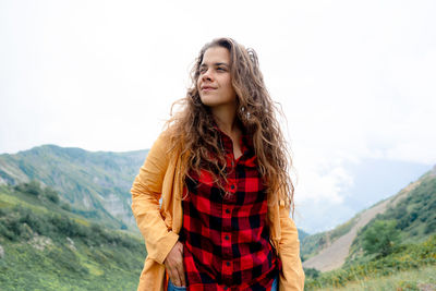 Young woman standing against mountain