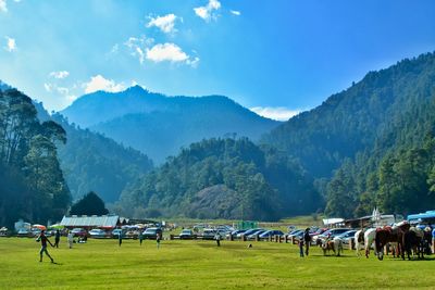 People on field by mountains against sky