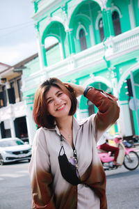 Portrait of smiling young woman standing in city