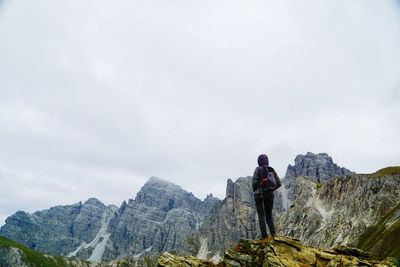 Rear view of woman standing on cliff against sky