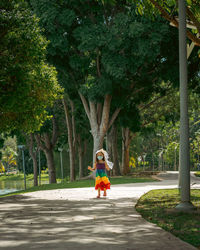 A little girl in a rainbow dress fun walking on the concrete path in the park.