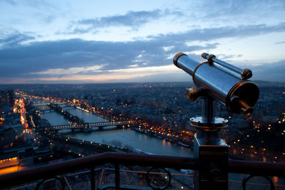 Close-up of hand-held telescope against cityscape and cloudy sky