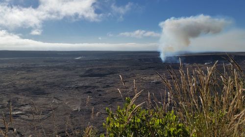 Smoke emitting from volcanic landscape against sky