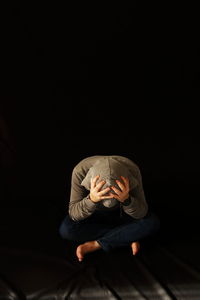 Stressed man sitting against black background