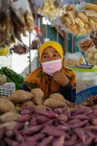 Woman seller wearing face mask at the local ingredients fresh food stall.