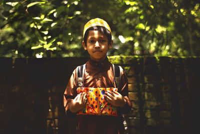 Portrait of boy holding koran against brick wall