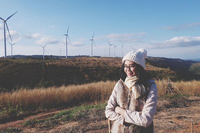 Woman wearing warm clothing while standing against windmills on mountain