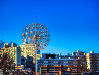 Ferris wheel in city against blue sky