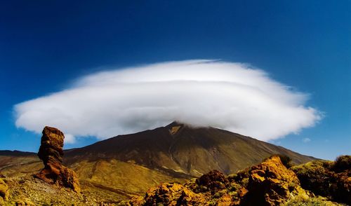 Scenic view of volcanic mountain against blue sky