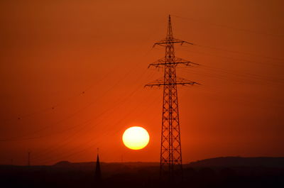 Low angle view of electricity pylon against sky during sunset