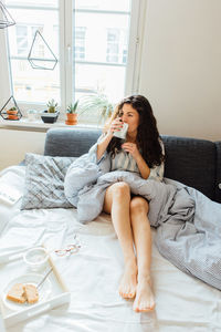 Woman having breakfast on bed at home