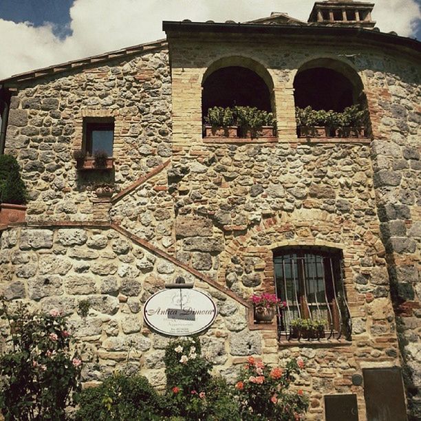 architecture, building exterior, built structure, window, arch, brick wall, residential building, low angle view, house, residential structure, building, old, stone wall, facade, sky, entrance, day, plant, wall - building feature, outdoors