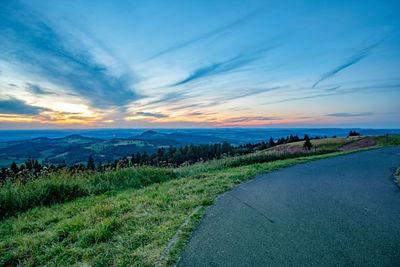 Road by land against sky during sunset