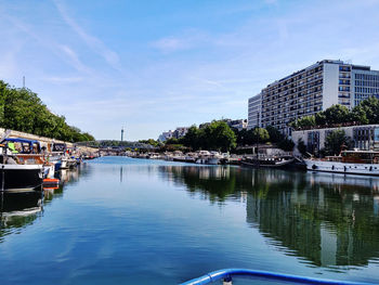 Scenic view of river by buildings against sky