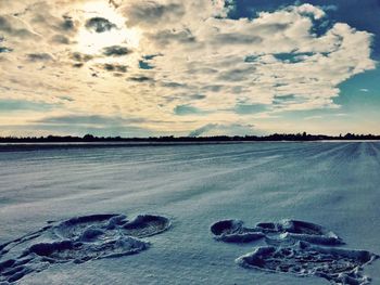 Scenic view of frozen beach against sky during sunset