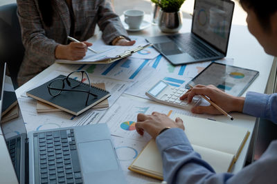 Midsection of business colleagues working on table