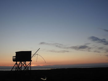 Silhouette tower on beach against sky during sunset