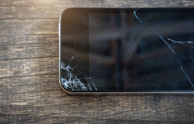 Close-up of cracked screen of mobile phone on table