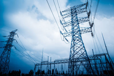 Low angle view of silhouette electricity pylon against sky