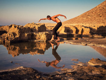 Reflection of man on rock against sky