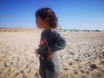 Girl standing on beach against clear sky