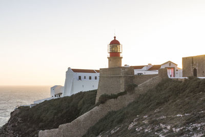 Lighthouse by sea against clear sky