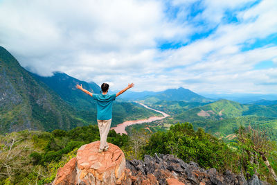 Rear view of man standing on rock against mountain