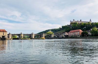 Arch bridge over river against buildings in city