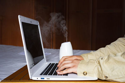 Midsection of man using laptop on table