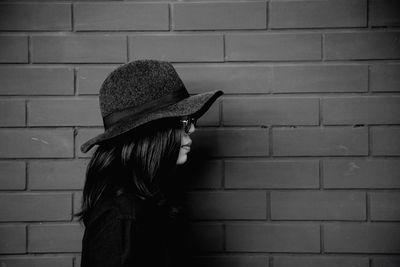 Side view of woman wearing hat against wall