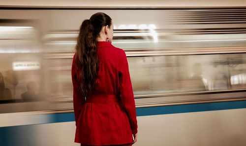 Rear view of woman standing at railroad station platform