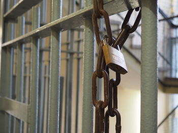 Close-up of lock attached to chain hanging on prison bars