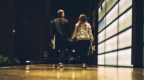 Rear view of people walking in illuminated corridor