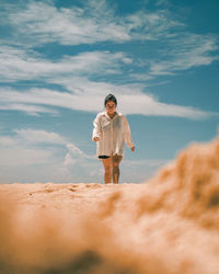 Rear view of woman standing at beach against sky