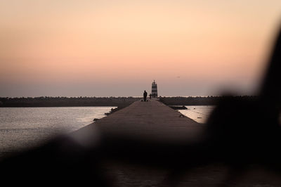 Silhouette people on beach against sky during sunset