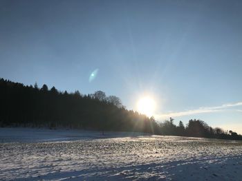 Snow covered landscape against sky during sunset