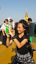 Portrait of smiling young woman standing against sky